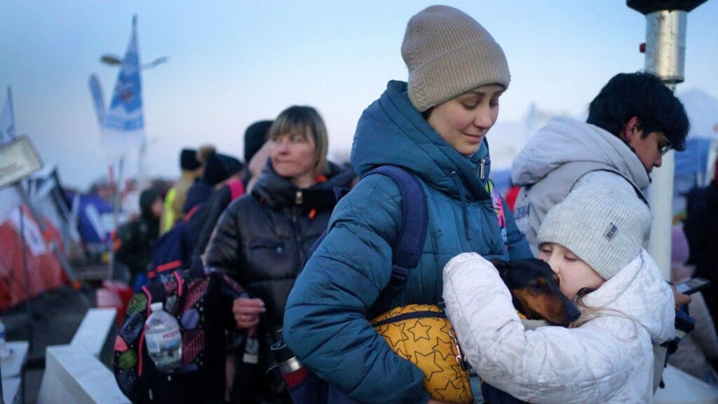 Молода дівчина з України чекає зі своєю матір'ю та собакою після перетину кордону з Польщею у 2022 році. Фото: PA